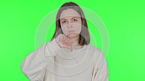 Thumbs Down by Young Woman on Green Background