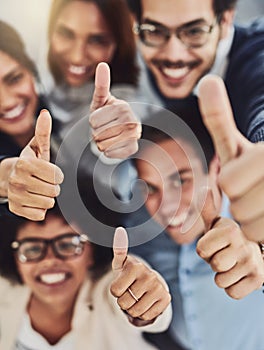 Thumbs up from a happy business team excited about the success they achieve together at work. Overhead view diverse