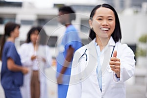 Thumbs up, happy and portrait of a doctor outdoor of the hospital with a leadership mindset. Happy, smile and Asian