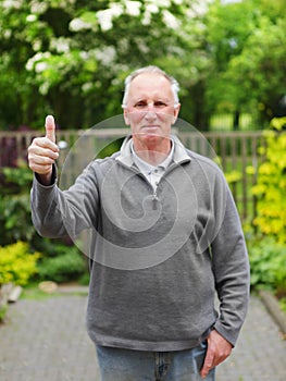 Thumbs up old man in garden