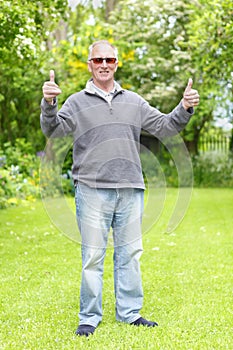 Thumbs up old man in garden