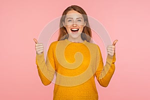 Thumbs up! Portrait of attractive cheerful ginger girl in sweater doing like gesture with finger up, expressing approval