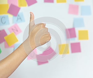 Thumbs up by right hand with frame of blank sticky note , which is used for education, business, communication  is stuck around