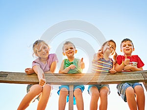 Thumbs up for some summer fun. Portrait of a group of little children showing thumbs up while playing together outdoors.