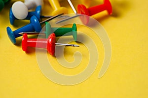 Thumbtacks of different colors on yellow background close-up macro copy space