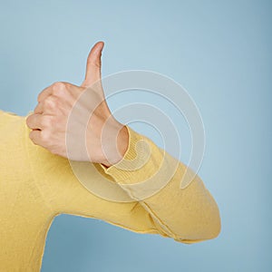 Thump up hand sign isolated on blue background. Copy space for your text