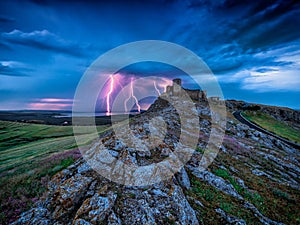 Thunderbolts lightning on a cloudy evening blue sky over old Enisala stronghold citadel