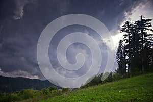 Thundercloud over a green meadow and large trees in the legendary ancient Greek Colchis