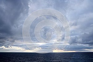 Thunderclouds and rain clouds over the sea horizon and the surface of the Pacific Ocean.