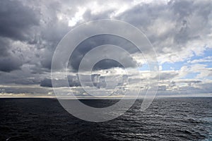 Thunderclouds and rain clouds over the sea horizon and the surface of the Pacific Ocean.