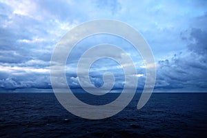 Thunderclouds and rain clouds over the sea horizon and the surface of the Pacific Ocean.