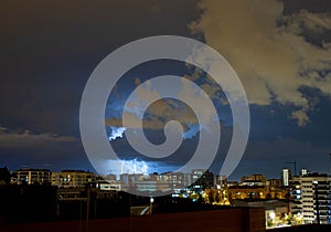 Thunders across the clouds behind the building