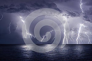 Thunderstorm with bright lightnings above sea water. Storm clouds in beautiful sky.