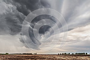 The thunderstorm clouds twisted in a spiral moving on over the field