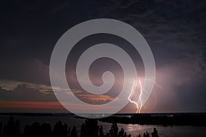 Thunderstorm and lightning strike over the river at night