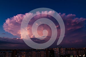 Thunderstorm in shape of explosion over the city on a warm summer evening. Cumulonimbus Incus cloud in a shape of nuclear mushroom