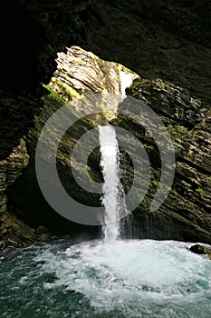 Thur waterfalls - waterfall on the rocks cascading down into a river from a sunlit hole