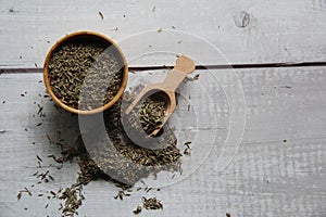 Thyme: dried in a wooden bowl with a wooden measuring spoon on a wooden table. photo