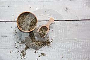 Thyme: dried in a wooden bowl with a wooden measuring spoon on a wooden table.
