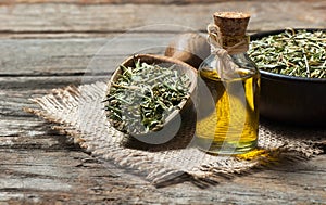 Thyme essential oil and Heap of dry thyme in wooden spoon and in bowl on wooden background