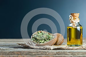 Thyme essential oil and Heap of dry thyme in wooden spoon or shovel on wooden background