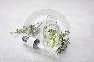 Thyme essential oil on light grey table