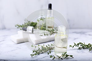 Thyme essential oil on white marble table, space for text