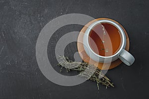 Thyme herbal tea on a black stone background, top view, space for a text