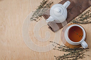 Thyme herbal tea in a white cup and teapot on a wooden table. Copyspace and top view