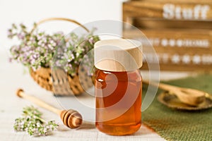 Thyme honey in a jar on a white wooden background