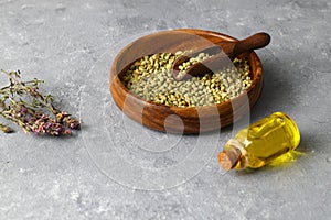 thyme(Oregano) essential oil and Heap of dry thyme in wooden spoon and in bowl on wooden background.