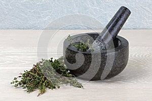 Thyme on wooden kitchen surface and mortar and pestle