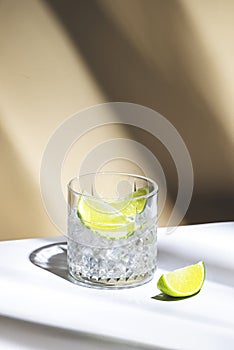 Ti punch cocktail drink with white rum agricole, sugar syrup and lime, traditional Caribbean beverage. Beige background, palm