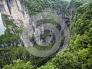 The Tianmen Mountain with a view of the cave Known as The Heaven`s Gate surrounded by the green forest and mist at Zhangjiagie, H