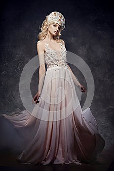 Tiara crown on head blonde girl. Woman in fairy dress, mysterious magical fairy. Ethnic blond woman on gray background