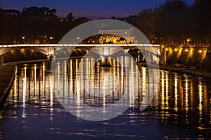 Tiber River, bridge and reflections on water. Night Rome, Italy.