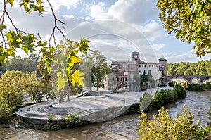 Tiberina Island, surrounded by vegetation and trees washed by water of the Tiber River in the capital of Italy, Rome