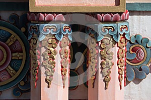 Nepal, Tibetan buddhist ornamented orange pillars and Chackra wheel in the background.