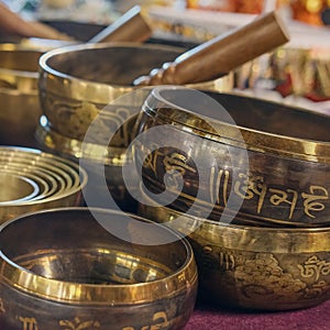 Tibetan healing singing bowls with selective focus to one with mantra sanskrit engraving pattern.