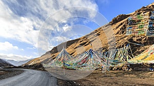 Tibetan landscape in China with prayer flags on foreground and a road on left side