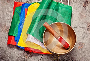 Tibetan prayer flags and singing bowl on a gray concrete background