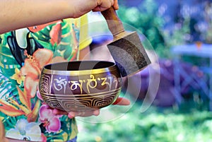 Tibetan singing bowl with Buddhist mantra in man`s hand