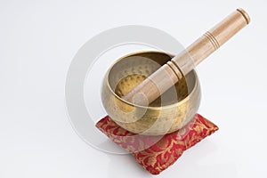 Tibetan Singing Bowl on Red Cushion and Wooden Mallet Isolated on White Background
