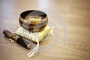 Tibetan Singing Bowl on Silk Yellow Pillow Cushion and Wood Background