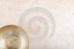 Tibetan singing bowl used during mantra meditations on beige stone background, top view, flat lay, copy space