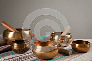 Tibetan singing bowls with mallets on colorful fabric, space for text