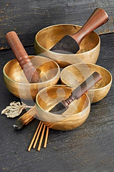 Tibetan singing bowls with palo santo, white sage and aroma sticks on the dark background. Music instruments for meditation, yoga