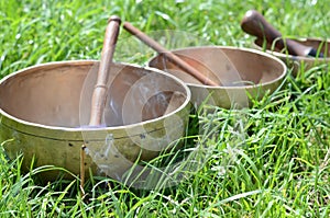 Tibetan singing bowls with sticks on the grass - music instruments for meditation, relaxation after yoga practice and healing