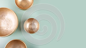 Tibetan singing bowls used during mantra meditations on green background, top view, copy space, web banner