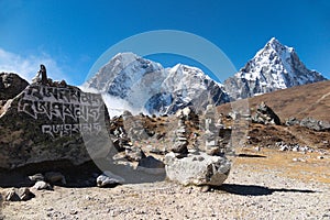 Tibetan stone cairns, prayer flags & rock with carved mantra `Six Syllables of Clairvoyance`, Thukla Pass, Everest Base Camp trek